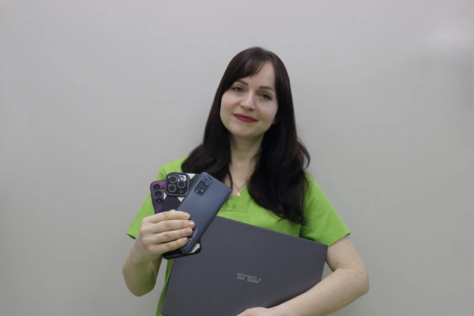 Жінка тримає ноутбук та кілька смартфонів