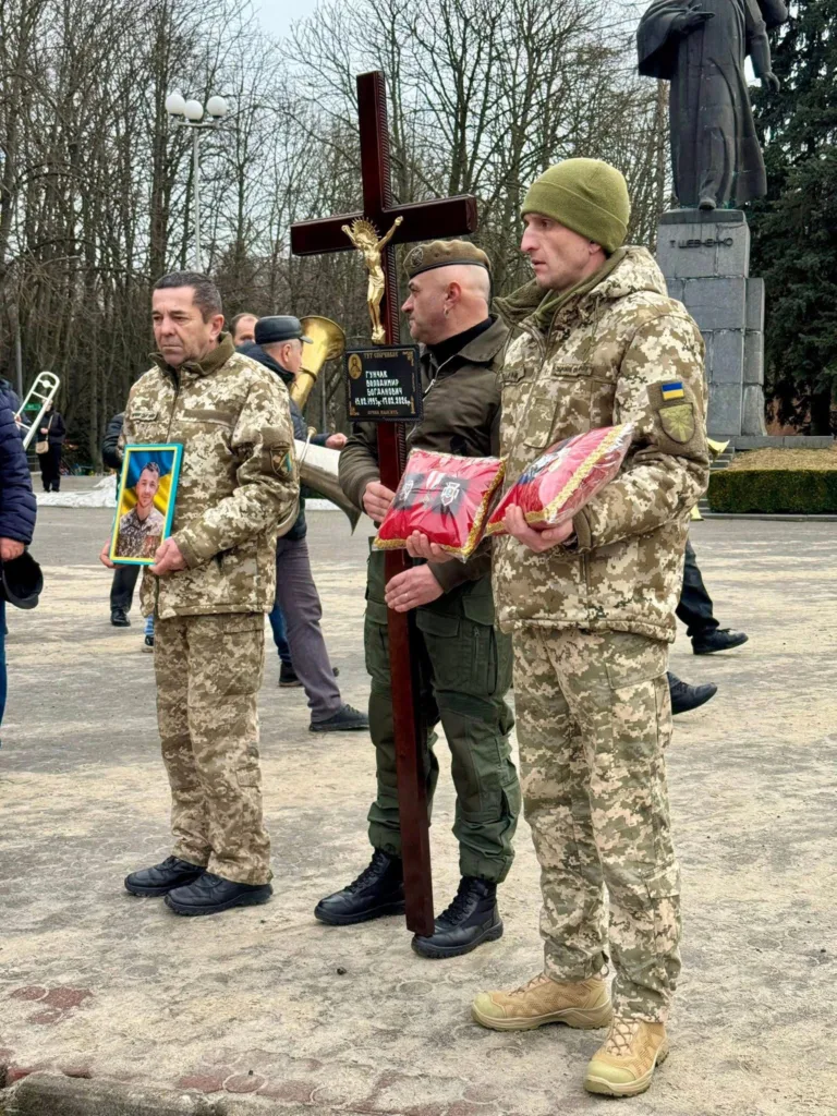 Військові тримають хрест і портрет загиблого героя