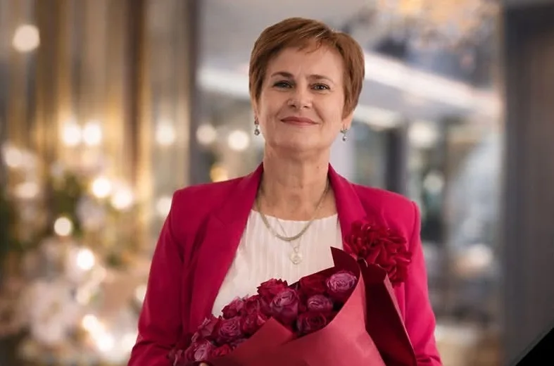 Жінка з букетом рожевих троянд у червоному піджаку