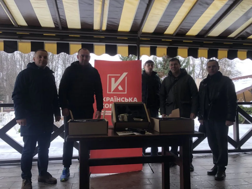 Група чоловіків біля червоного банера на терасі