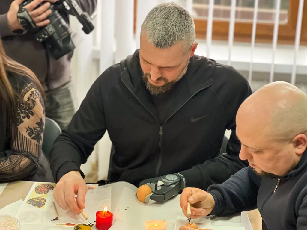 Люди розписують писанки біля свічки