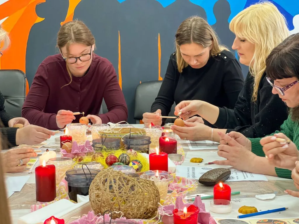 Люди розписують писанки за святковим столом