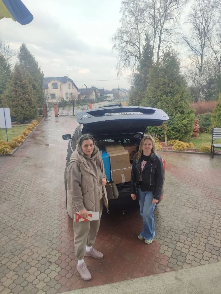 Дві жінки біля автомобіля з гуманітарною допомогою