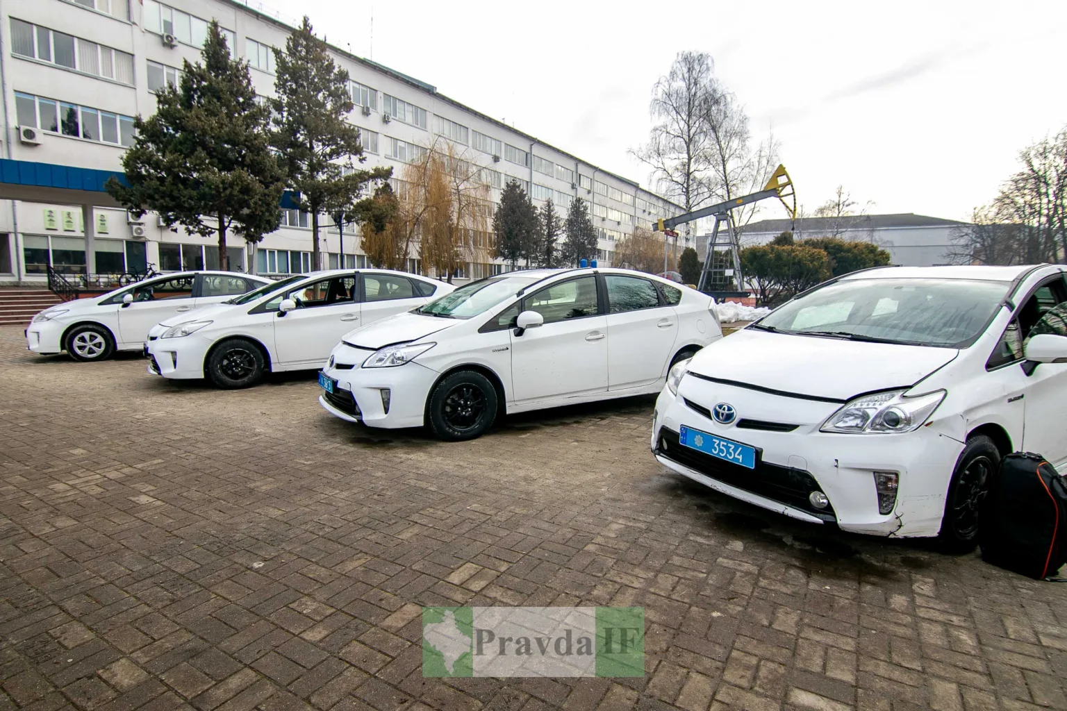 Білі гібридні авто біля адміністративної будівлі