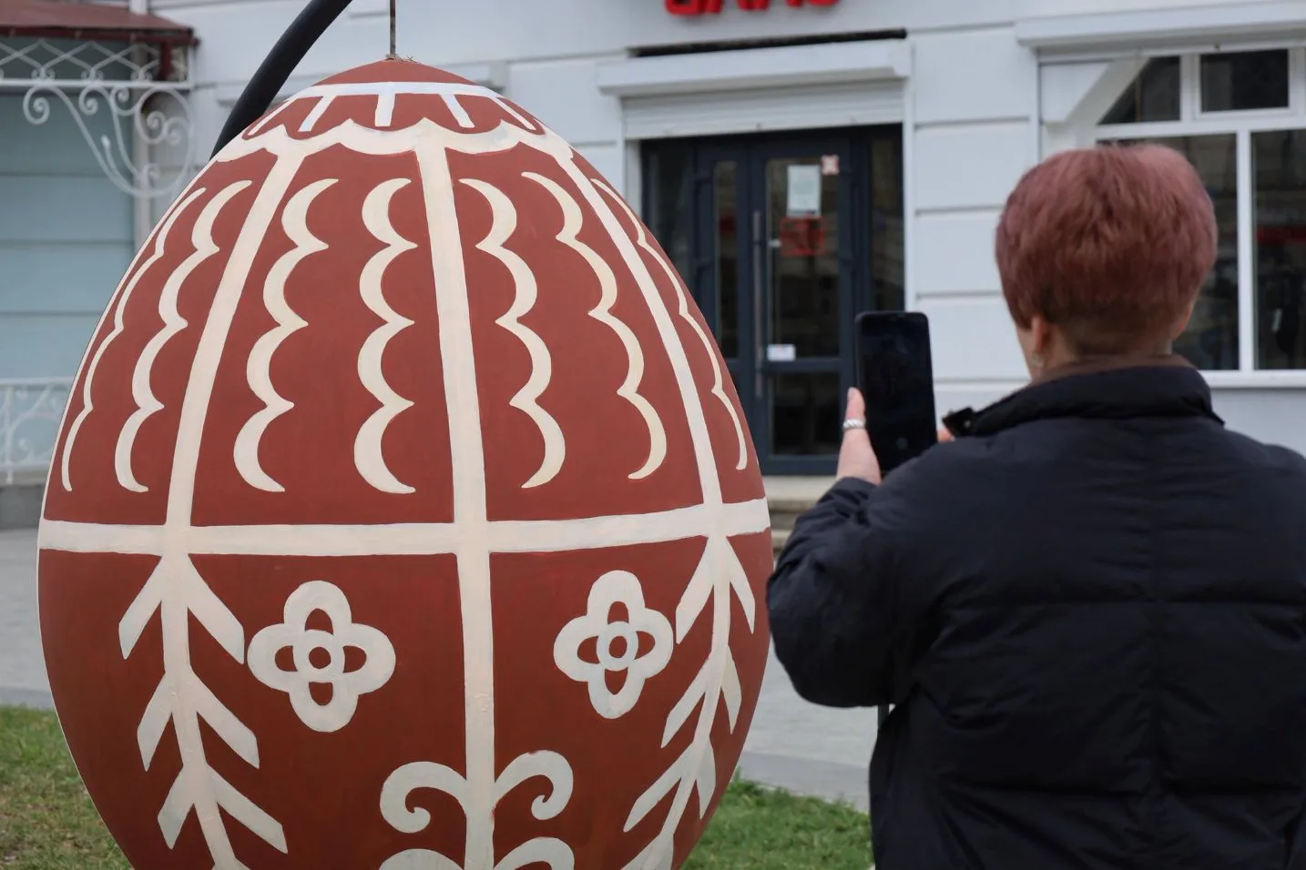 Жінка фотографує велику декоративну писанку на вулиці