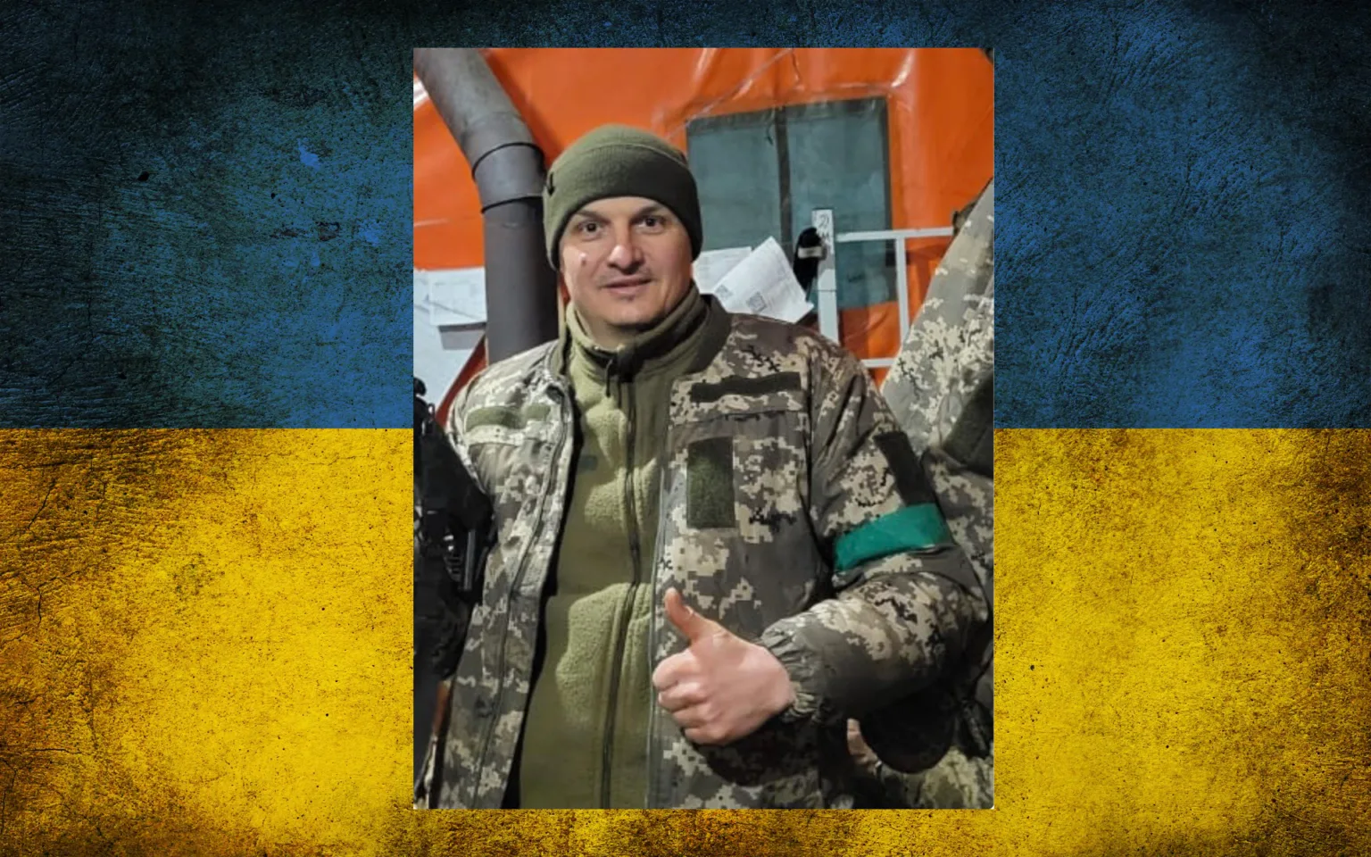 Український військовий у камуфляжі на фоні прапора