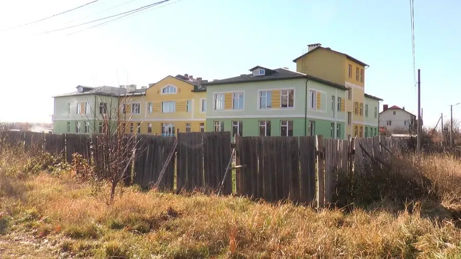 Нова триповерхова будівля біля дерев’яного паркану