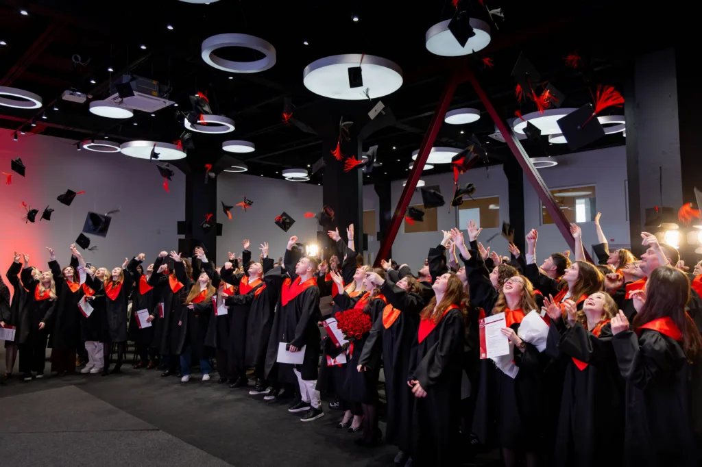 Випускники святкують, кидаючи капелюхи в повітря