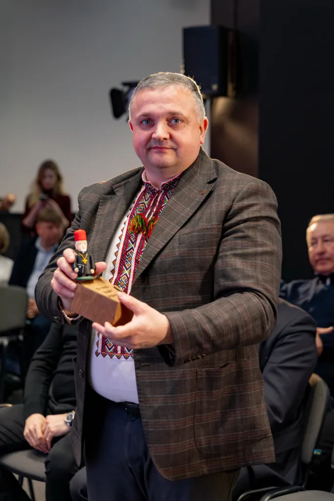 Чоловік у вишиванці тримає дерев'яну фігурку