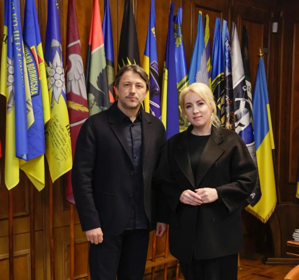 Двоє людей стоять перед прапорами України