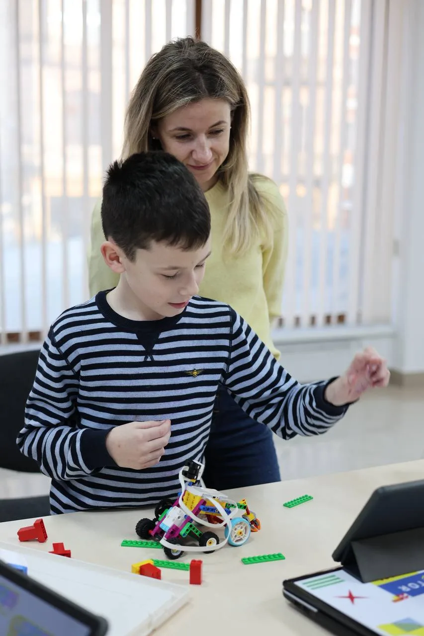 Хлопчик збирає робот з LEGO на уроці STEM