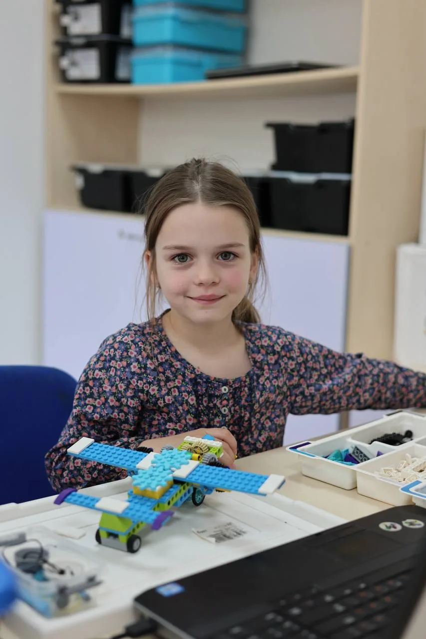 Дівчинка збирає літак з конструктора LEGO