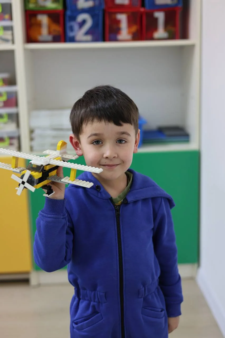 Хлопчик тримає літак з конструктора LEGO