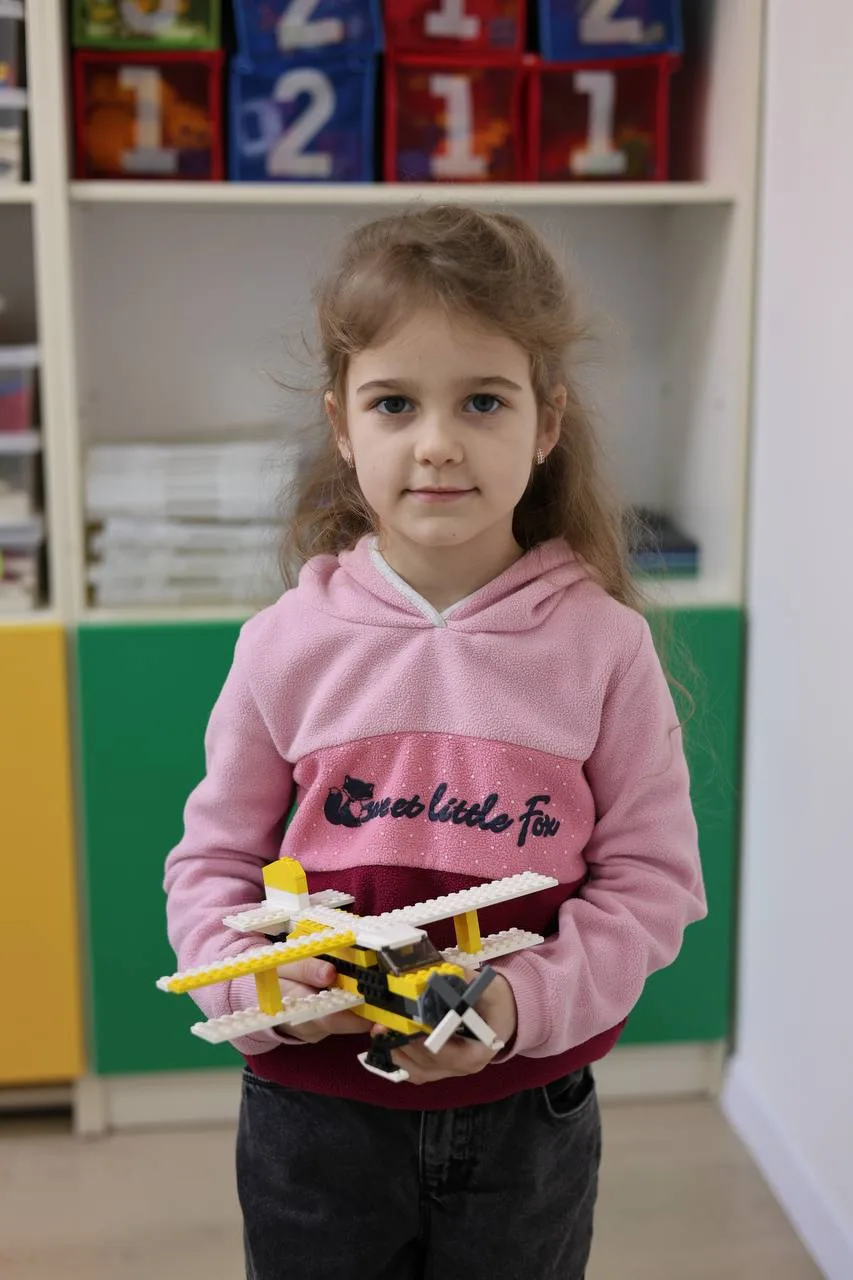 Дівчинка тримає іграшковий літак із LEGO