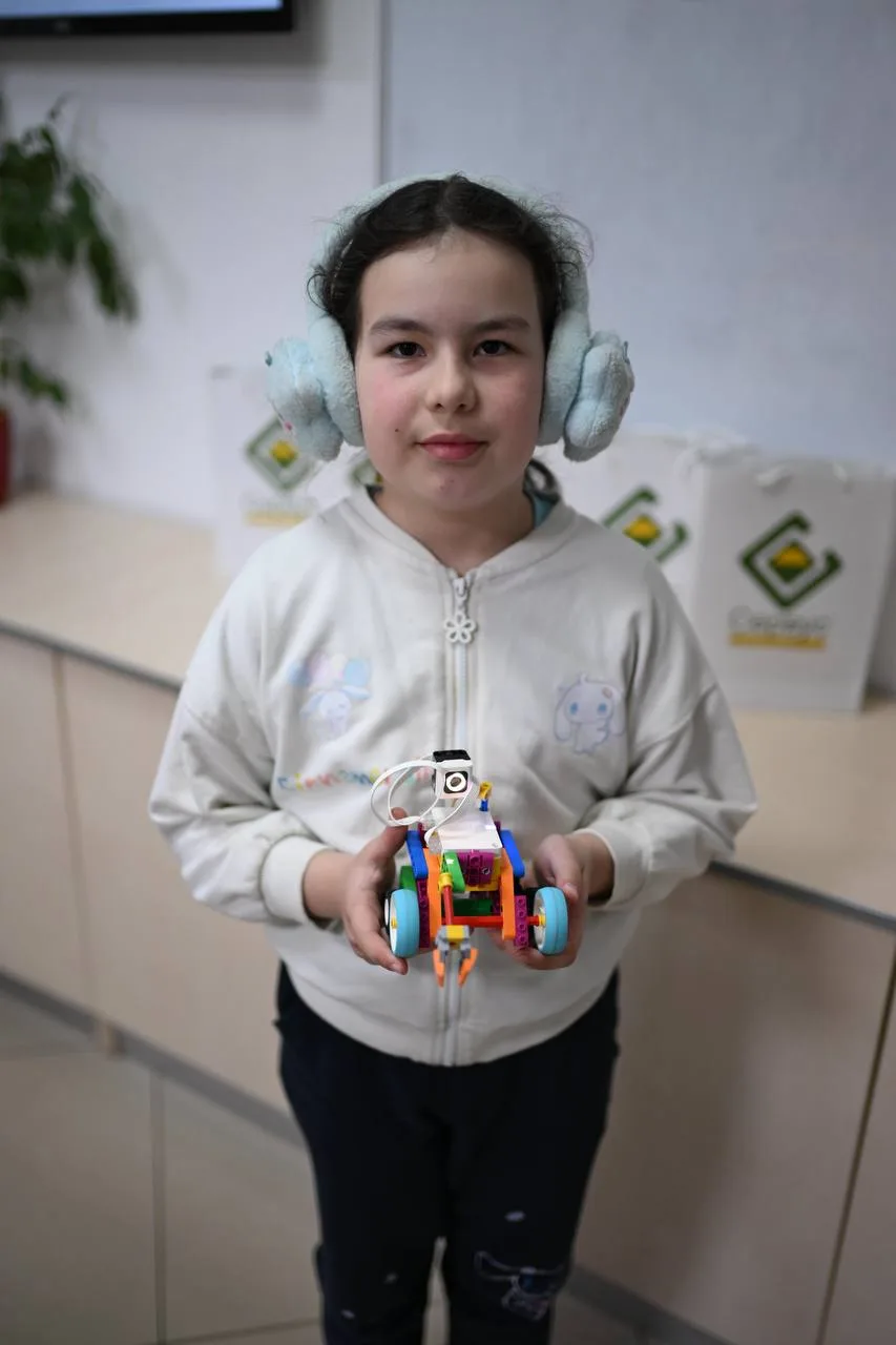 Дівчинка показує саморобного робота з конструктора
