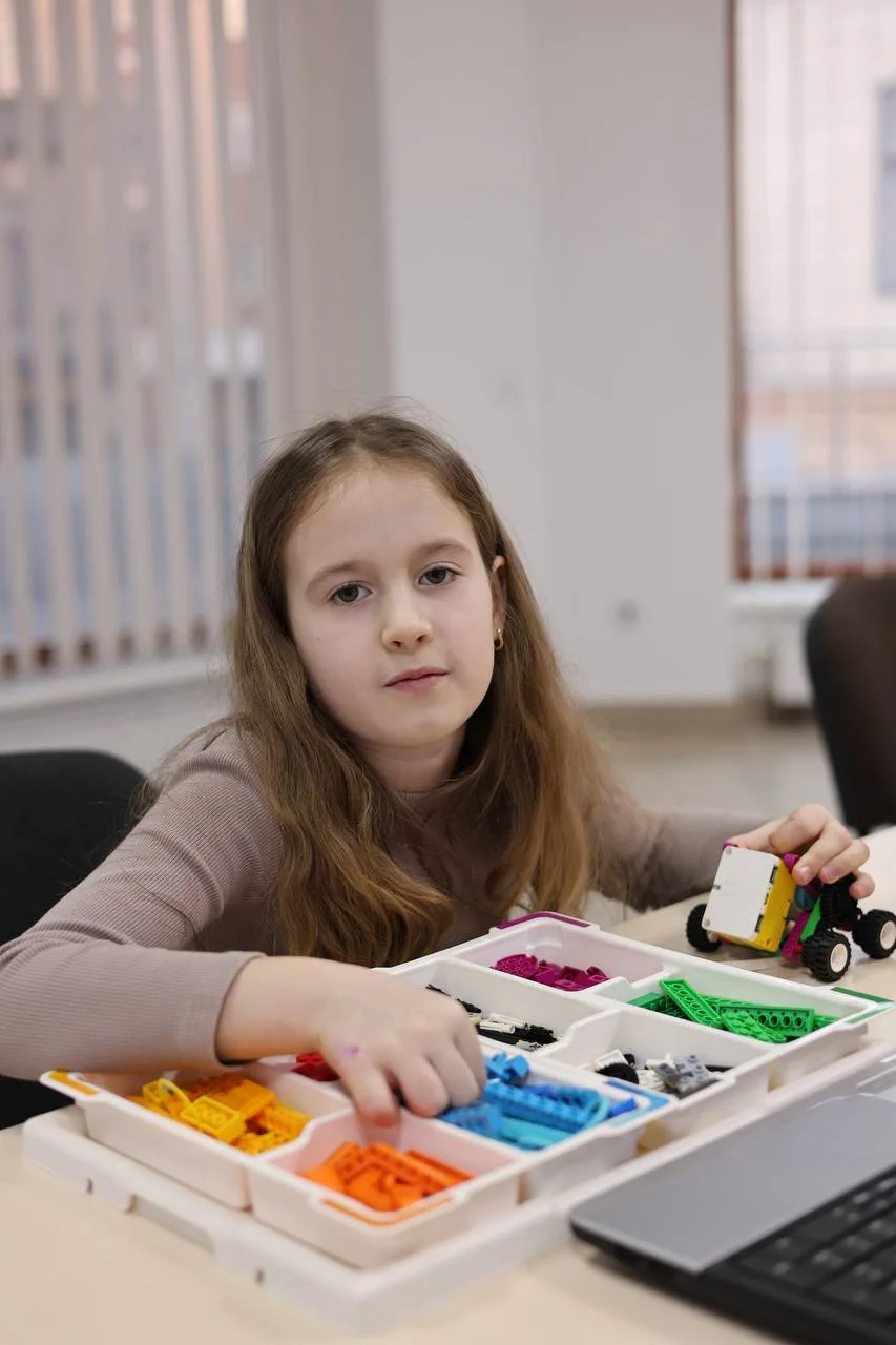 Дівчинка збирає робот із кольорових деталей LEGO
