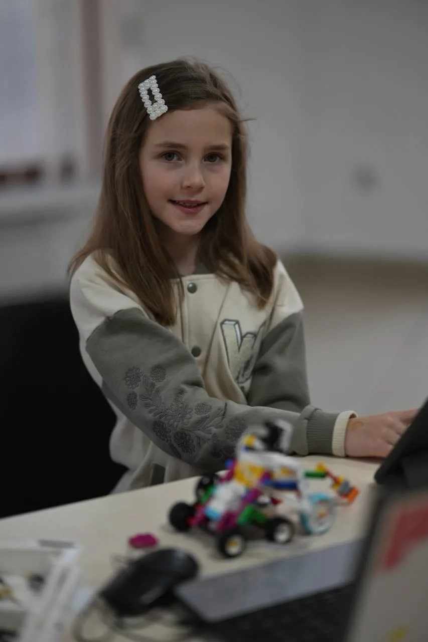 Дівчинка збирає LEGO робот на столі