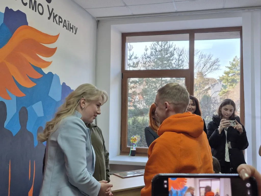 Люди спілкуються у яскравій кімнаті з малюнком крила