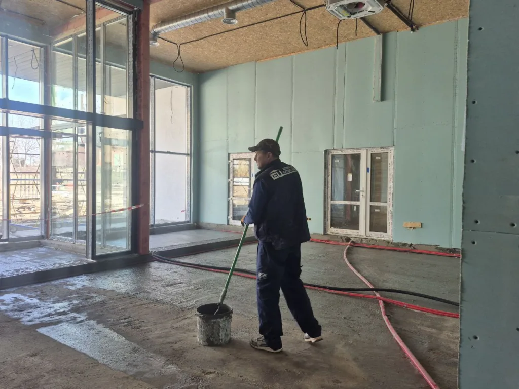 Робітник миє підлогу всередині будівлі на ремонті