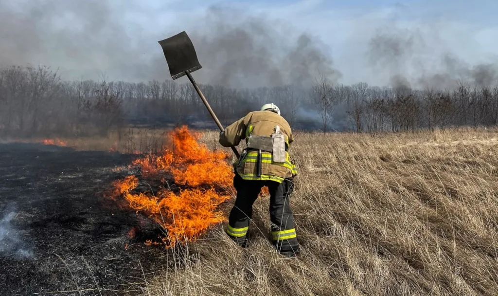 Пожежник гасить вогонь на сухій траві