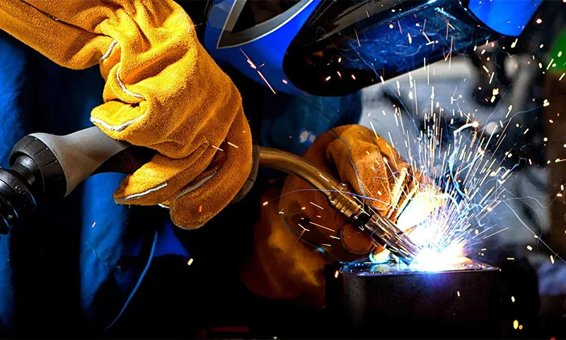 Зварювальник працює з металом, іскри під час зварювання