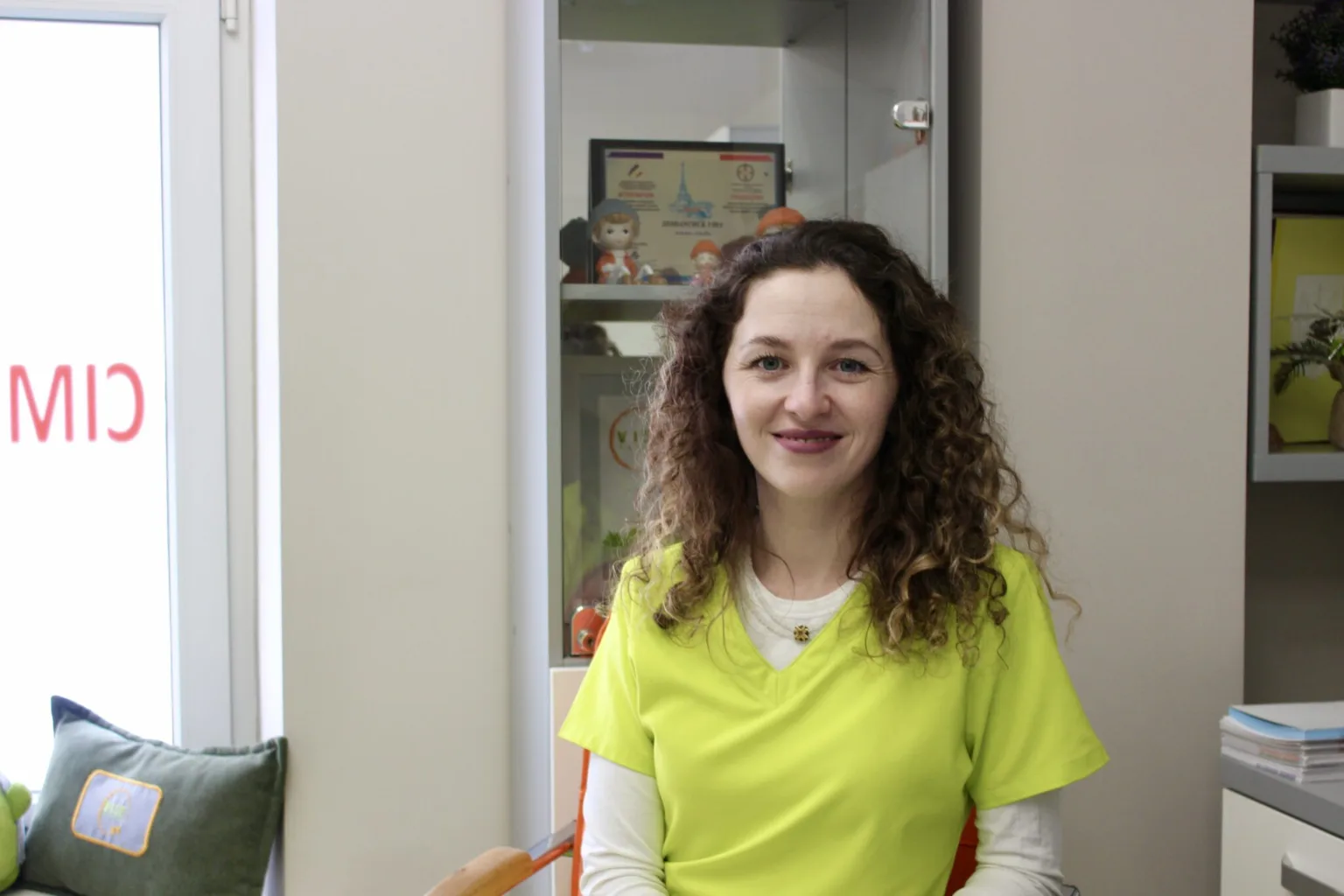 Жінка у жовтому одязі сидить в офісі