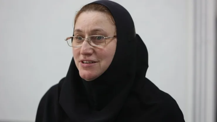 Жінка в чорній хустці та окулярах говорить