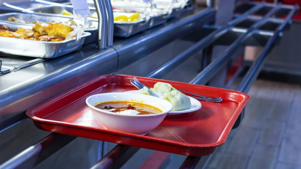 Суп і пельмені на червоному підносі в їдальні