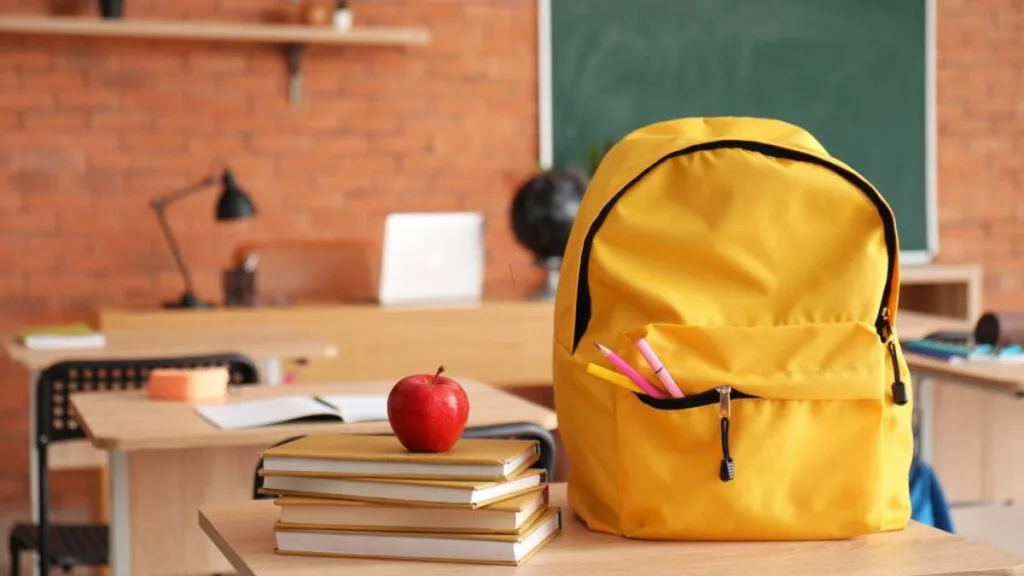 Жовтий рюкзак і книги на столі в класі