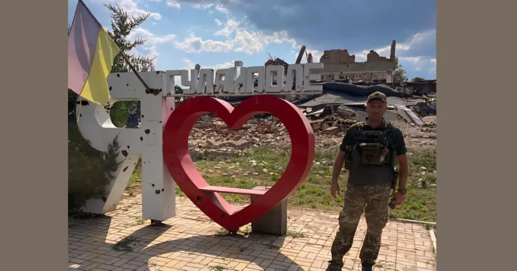 Військовий біля знаку Гуляйполе серед руїн