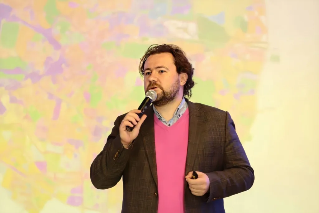 Чоловік виступає з мікрофоном на кольоровому тлі