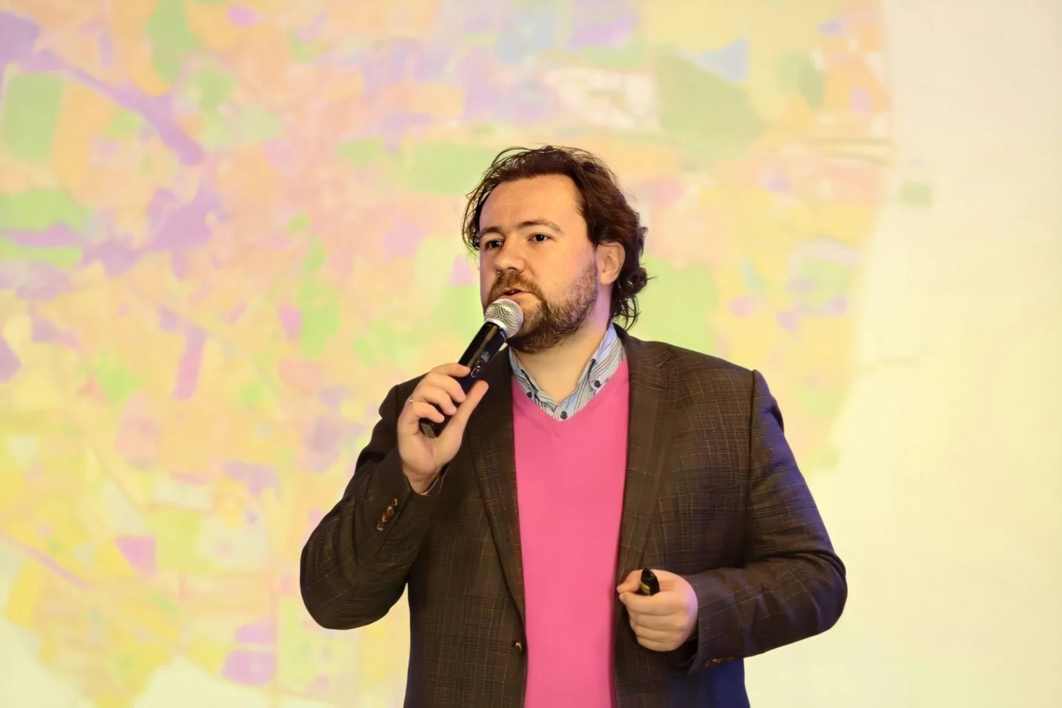 Чоловік виступає з мікрофоном на кольоровому тлі