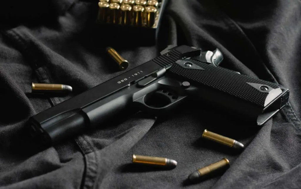 Чорний пістолет і кулі на темному одязі