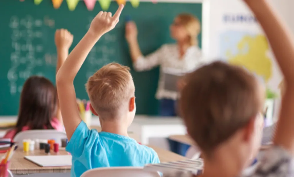 Діти піднімають руки на уроці в школі