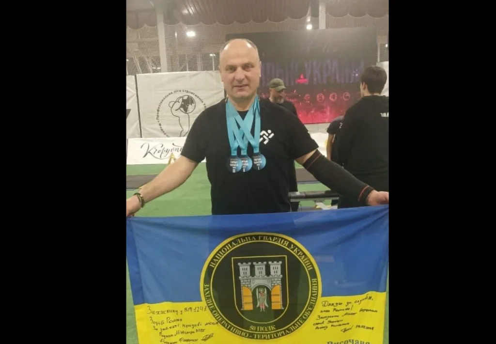 Спортсмен із медалями тримає прапор Нацгвардії України