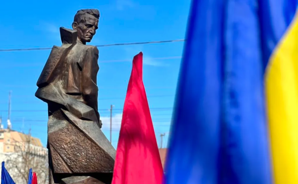 Пам’ятник перед українським і червоним прапорами