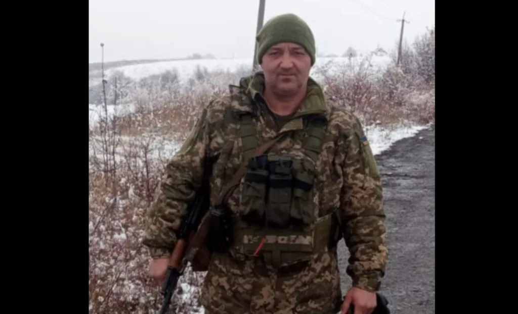 Військовий у камуфляжі стоїть на засніженій дорозі