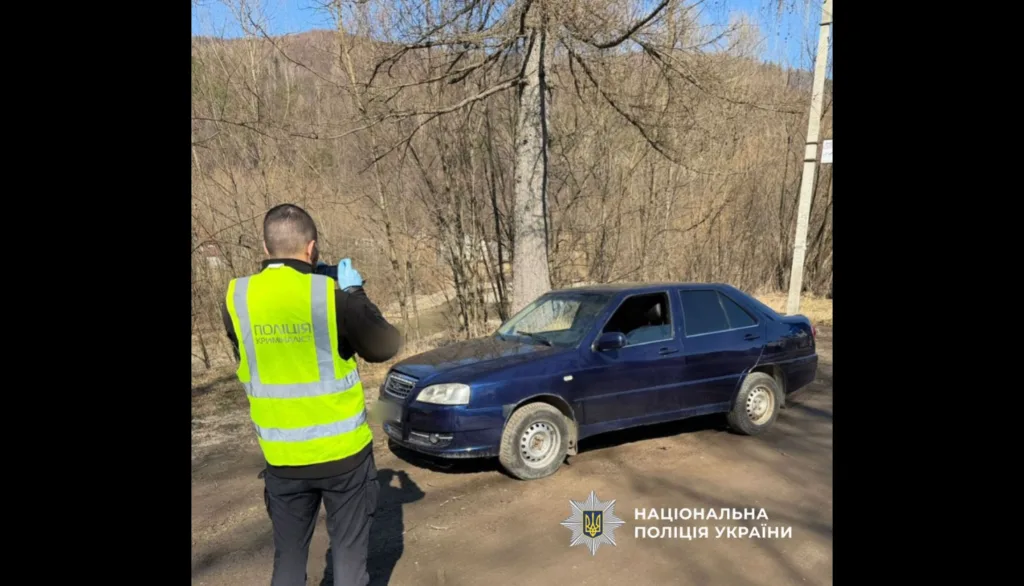 Поліцейський оглядає синій автомобіль на дорозі