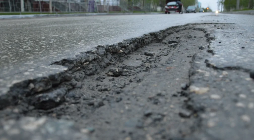 Пошкоджене дорожнє покриття з глибокою вибоїною