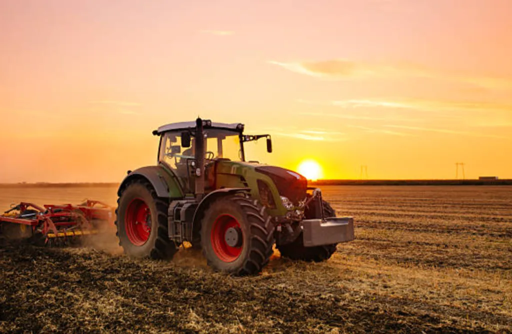 Трактор оре поле на заході сонця