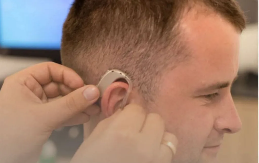 Фахівець встановлює слуховий апарат чоловікові