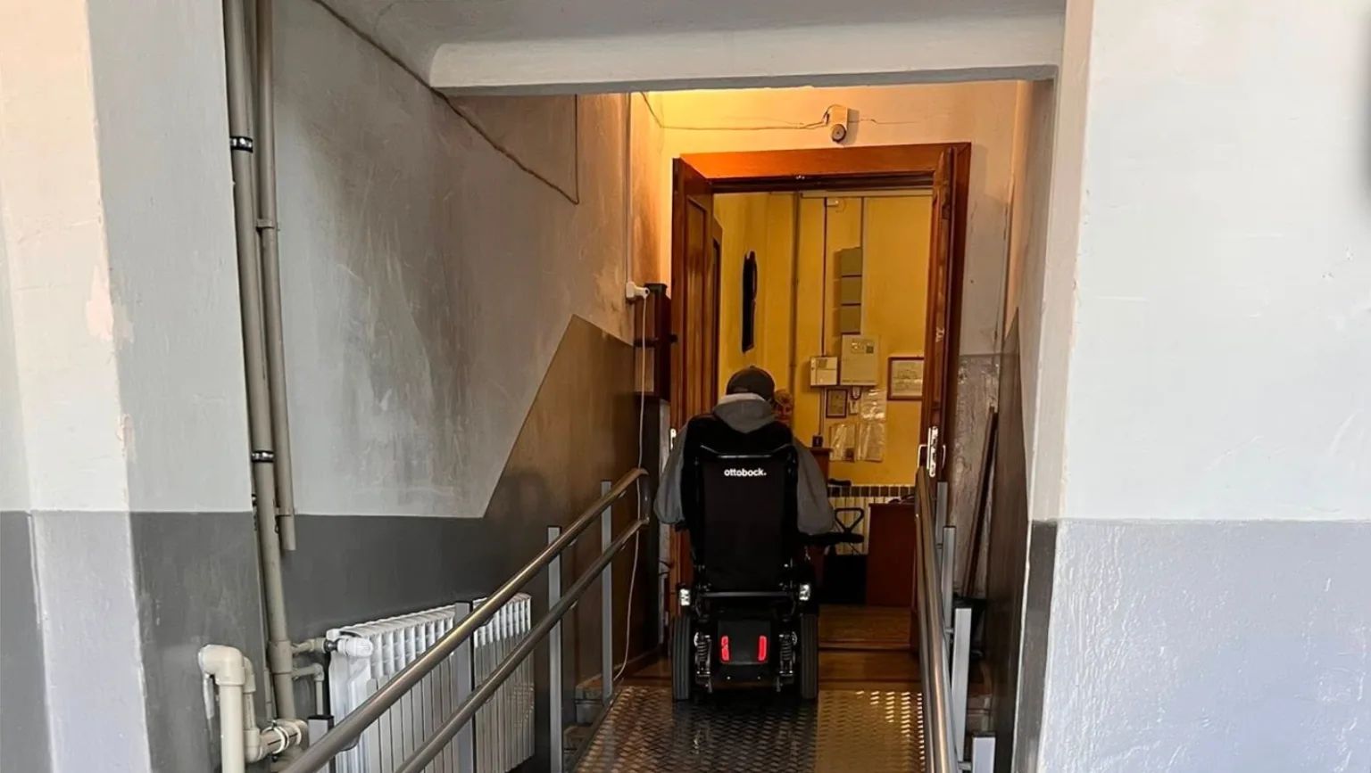 Людина на інвалідному візку користується пандусом всередині будівлі