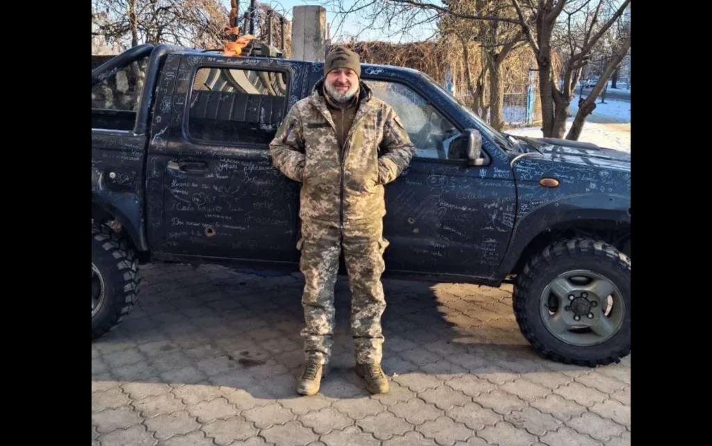 Військовий стоїть біля позашляховика з написами