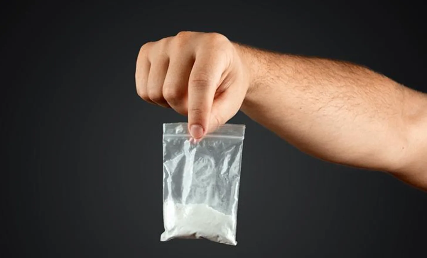 Рука тримає пакет з білим порошком