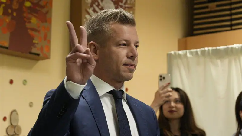 Чоловік у костюмі показує знак миру