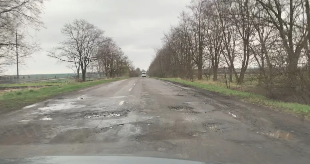 Пошкоджена сільська дорога з ямами навесні