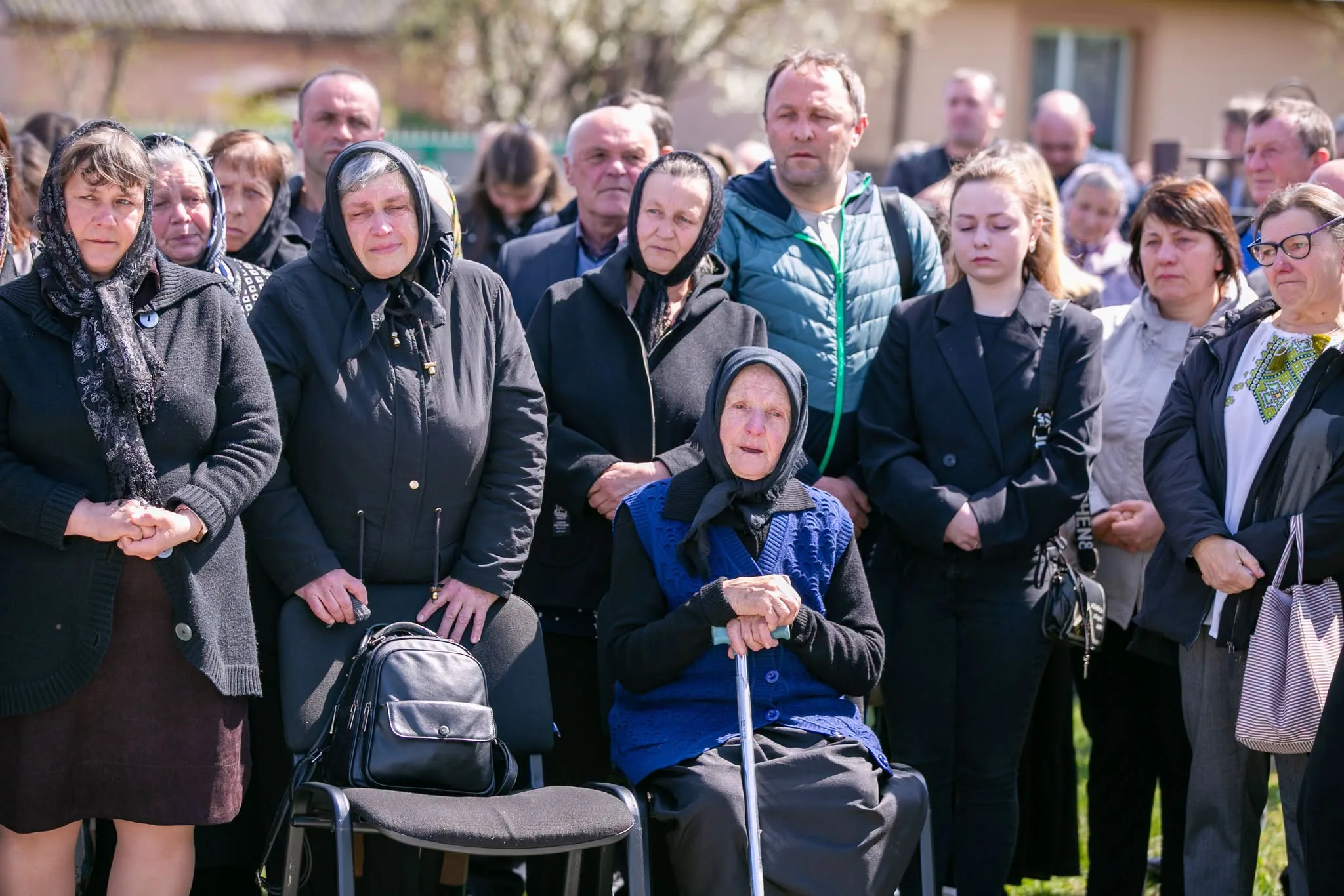 Люди на похороні на вулиці під сонцем