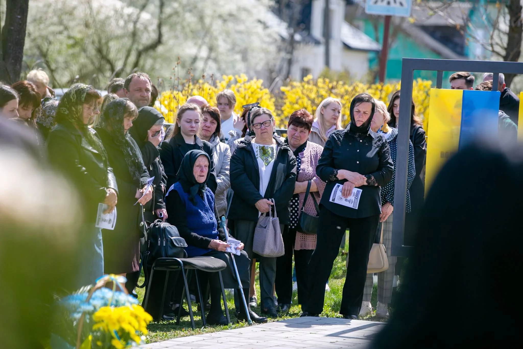 Люди на жалобній церемонії біля українського прапора
