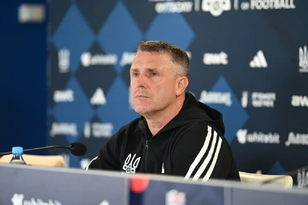 Чоловік на пресконференції у спортивній куртці