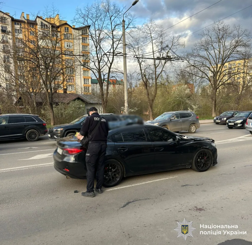 Поліцейський перевіряє документи біля чорного автомобіля